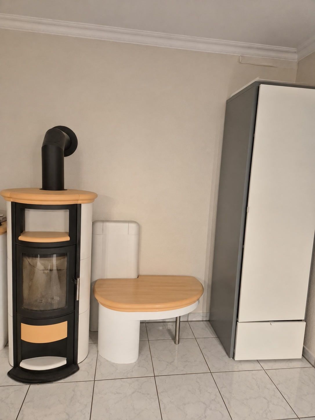 Kaminofen mit Holzabdeckung, halbrunde Sitzbank und hoher Kleiderschrank.